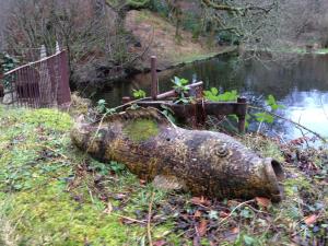 a large log in the grass next to a river at Ard Na Mara Self Catering Isle of Mull in Dervaig