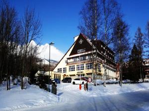 un grande edificio nella neve di fronte a una strada di Hotel Sasanka a Tatranská Lomnica