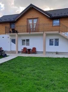 une maison avec une terrasse et une table devant elle dans l'établissement Cabana plaiului, à Vişeu de Sus