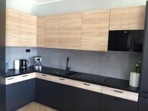 a kitchen with black counter tops and wooden cabinets at Apartament Malta Poznań in Poznań