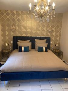 a bedroom with a large bed with a chandelier at LE TOUT JOLI NID BEAUNOIS, Studio Plein centre parking in Beaune