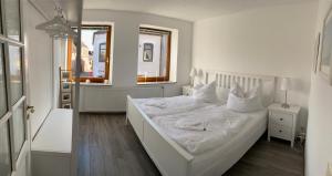 a white bedroom with a bed with white sheets and pillows at Gasthaus Hafenblick in Tönning