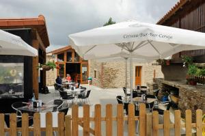 un patio con mesas, sillas y una sombrilla en Albergue El Aleman en Boente