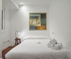 a white bed in a room with a painting on the wall at Idiakez - Basque Stay in San Sebastián