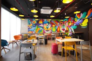 a restaurant with tables and chairs and a colorful wall at ibis budget Bogota Marly in Bogotá