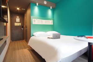 a bedroom with a white bed with a blue wall at ibis budget Bogota Marly in Bogotá