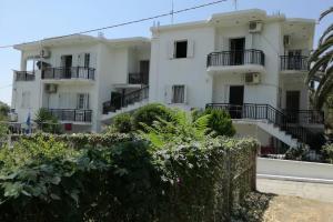 - un bâtiment blanc avec des balcons et des buissons noirs dans l'établissement Αλεξανδρος 1, à Mirina