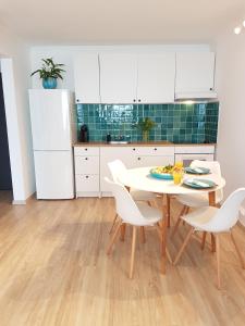 eine Küche mit einem weißen Tisch und weißen Stühlen in der Unterkunft Nett Apartman in Siófok