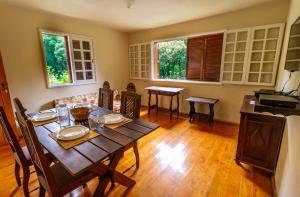 a dining room with a table and chairs and two windows at Chalés da Bocaina in Bananal