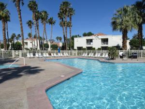 ein Pool mit Palmen und ein Gebäude in der Unterkunft Desert Breezes Resort in Palm Desert