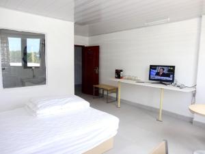 Habitación blanca con cama y escritorio con ordenador. en Airlines Business Hotel en Port Vila