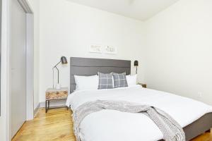 a white bedroom with a large bed with a gray headboard at Sonder Telfair Square in Savannah