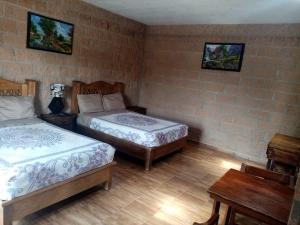 a bedroom with two beds and a table and a table at Hotel La Cabaña in San Miguel de Allende