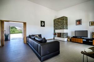 a living room with a leather couch and a fireplace at Villa Viana by Villa Plus in Lagoa