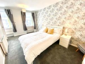 een slaapkamer met een bed met een witte sprei bij Cosy, Modern 2 Bedroom Apartment in the Centre of Inveraray in Inveraray