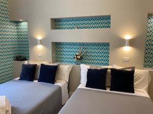 ナポリにあるAmbra Noblesseの青と白の壁紙を用いた客室内のベッド2台