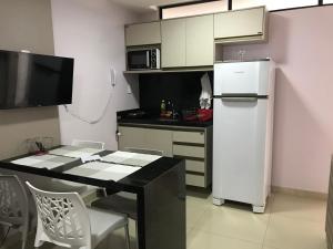 Il comprend une cuisine équipée d'un réfrigérateur blanc et d'une table avec des chaises. dans l'établissement Atlantico Flat Ap. 107, à Natal