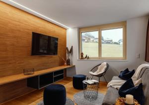 a living room with a flat screen tv on a wooden wall at Verwall Apartment Arlberg - mit Sauna in Wald am Arlberg