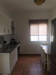 uma cozinha com armários brancos, uma mesa e uma janela em Casa Oliva Playa Bolonia em Tarifa