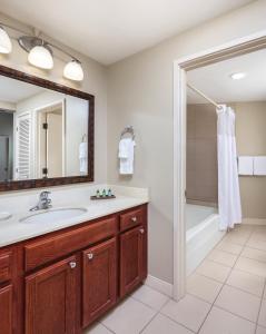 ein Badezimmer mit einem Waschbecken, einer Badewanne und einem Spiegel in der Unterkunft Wyndham Royal Sea Cliff Resort in Kailua-Kona