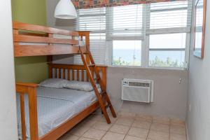 a bedroom with a bunk bed and two windows at Apartment in Villas Del Faro Resort with WIFI in Maunabo