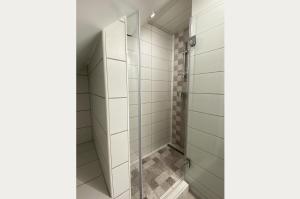 La salle de bains est pourvue d'une douche avec des portes en verre. dans l'établissement Andrea Apartmanok, à Hajdúszoboszló