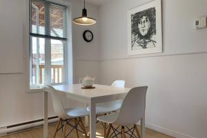 uma sala de jantar branca com uma mesa e cadeiras brancas em L'appartement BOHO avec parking em Cidade de Quebec