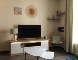 sala de estar con TV de pantalla plana en un centro de entretenimiento de madera en Ker Lomic, en Arzon