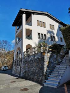 una casa bianca con un muro in pietra e scale di 1 Zimmer Apartment mit Seesicht und Pool a Vira Gambarogno