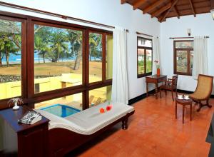ein Wohnzimmer mit Poolblick und einem Tisch in der Unterkunft Amritara The Poovath Beachfront Heritage, Fort Kochi in Kochi