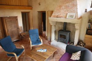 sala de estar con chimenea de piedra y sillas azules en Gîte de la Barlière, en Secondigny