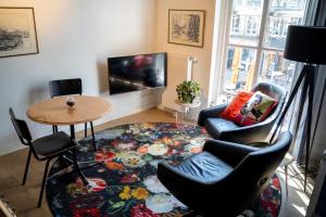 een woonkamer met een tafel en stoelen en een televisie bij Ginny's studio op de Grote Markt in Breda