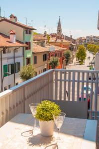 a table with wine glasses and a potted plant on a balcony at Appartamento Marchesini in Grado