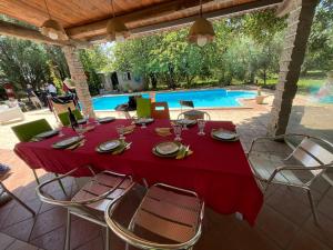 uma mesa com uma toalha de mesa vermelha e cadeiras ao lado de uma piscina em Loft mansardato con giardino e piscina in villa privata Loft with garden and swimming pool in a private villa em Sestu