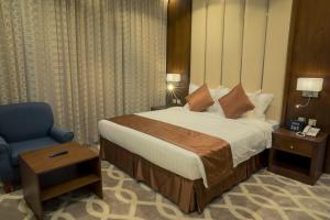 um quarto com uma cama e uma cadeira azul em 92 - وحدات فندقية - em Unaizah