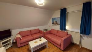 ein Wohnzimmer mit zwei roten Sofas und einem TV in der Unterkunft Finkennest Wolke 7 in Carolinensiel