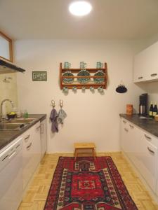 een keuken met witte kasten en een tapijt op de vloer bij Homely Apartment in the Center with Garden View in Gmunden