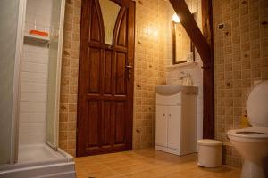 La salle de bains est pourvue de toilettes et d'une porte en bois. dans l'établissement Stajnia Swarzewo, à Swarzewo