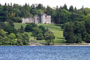 a castle sitting on top of a hill next to a lake at One bedroom Flat on the banks of Loch Lomond in Alexandria
