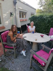 zwei Frauen sitzen an einem Tisch in Stühlen in der Unterkunft Villa Estee in De Haan