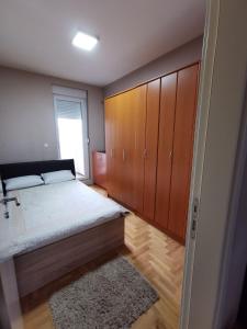 a bedroom with a bed and wooden cabinets and a rug at Mint in Sremska Mitrovica