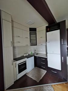 a kitchen with white cabinets and a white refrigerator at Mint in Sremska Mitrovica