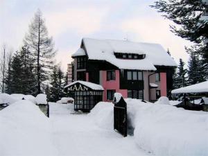 a house covered in snow in front at Pension MAAN in Tatranska Strba