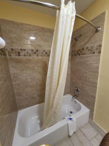 a bathroom with a white tub and a shower at America's Value Inn in Tulsa