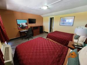 a hotel room with two beds and a desk at America's Value Inn in Tulsa