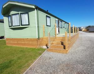 a green mobile home with a wooden deck at Ruan's Roost in Carlisle
