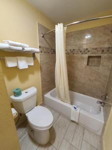 a bathroom with a toilet and a shower and a tub at America's Value Inn in Tulsa