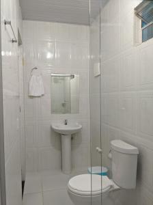 a white bathroom with a toilet and a sink at Hotel Flor de Lótus II in Santa Isabel do Pará