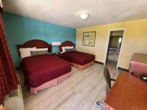 a hotel room with two beds and a desk at America's Value Inn in Tulsa