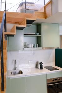 - une cuisine avec des placards verts et blancs et un évier dans l'établissement Adega Floresta Residence, à Porto